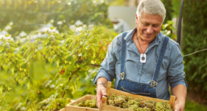 Man in vineyard, working with fresh grapes and smiling with CoxHealth at Home Lifeline button securely fasten around his neck
