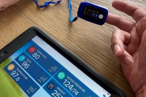 Patient's hand utilizing a heart rate monitor connected to a Remote Patient Monitor tablet